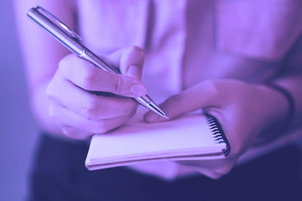 Photo of a woman writing on a pad with her fountain pen